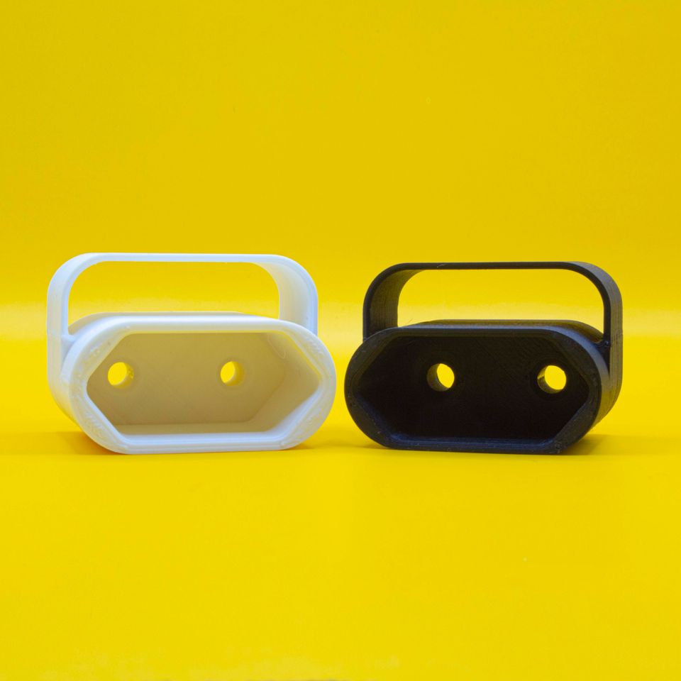 Studio photo of two 3D printed thingies (black and white) on a yellow backgroud